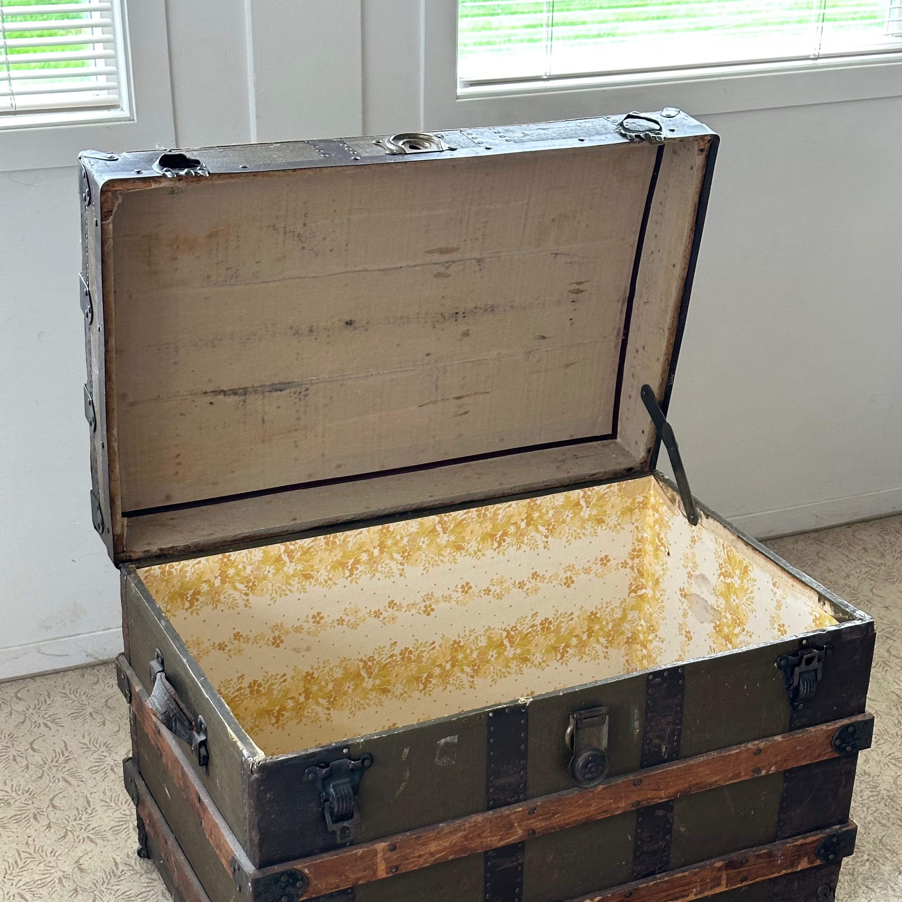Vintage trunk with a wooden interior on a concrete floor.