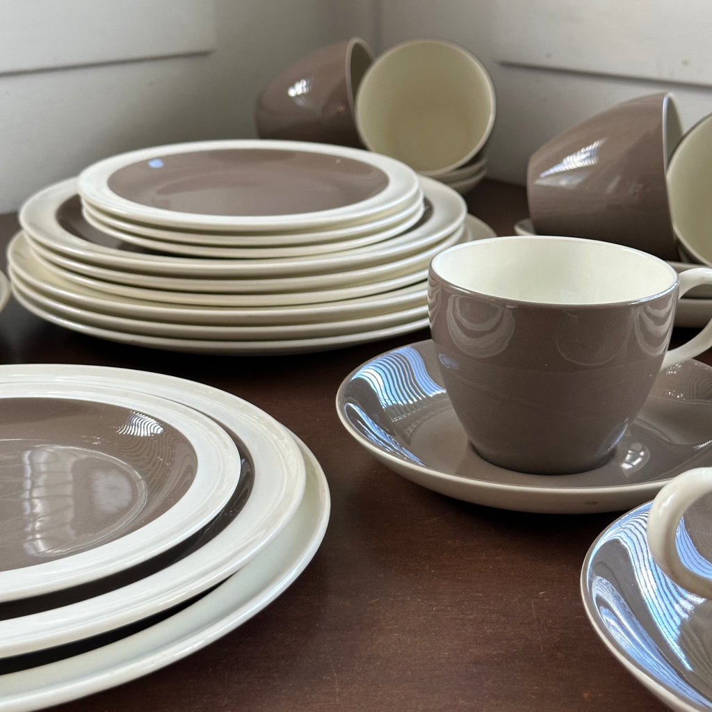 Set of brown and white wedgwood plates and cups on a wooden surface