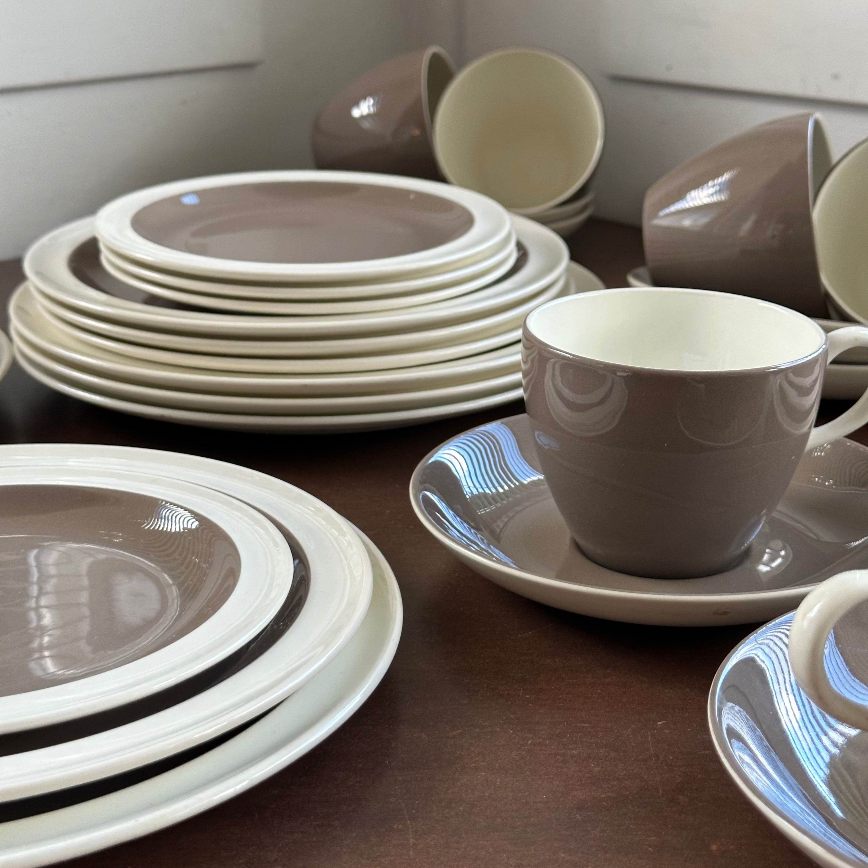 Set of brown and white wedgwood plates and cups on a wooden surface
