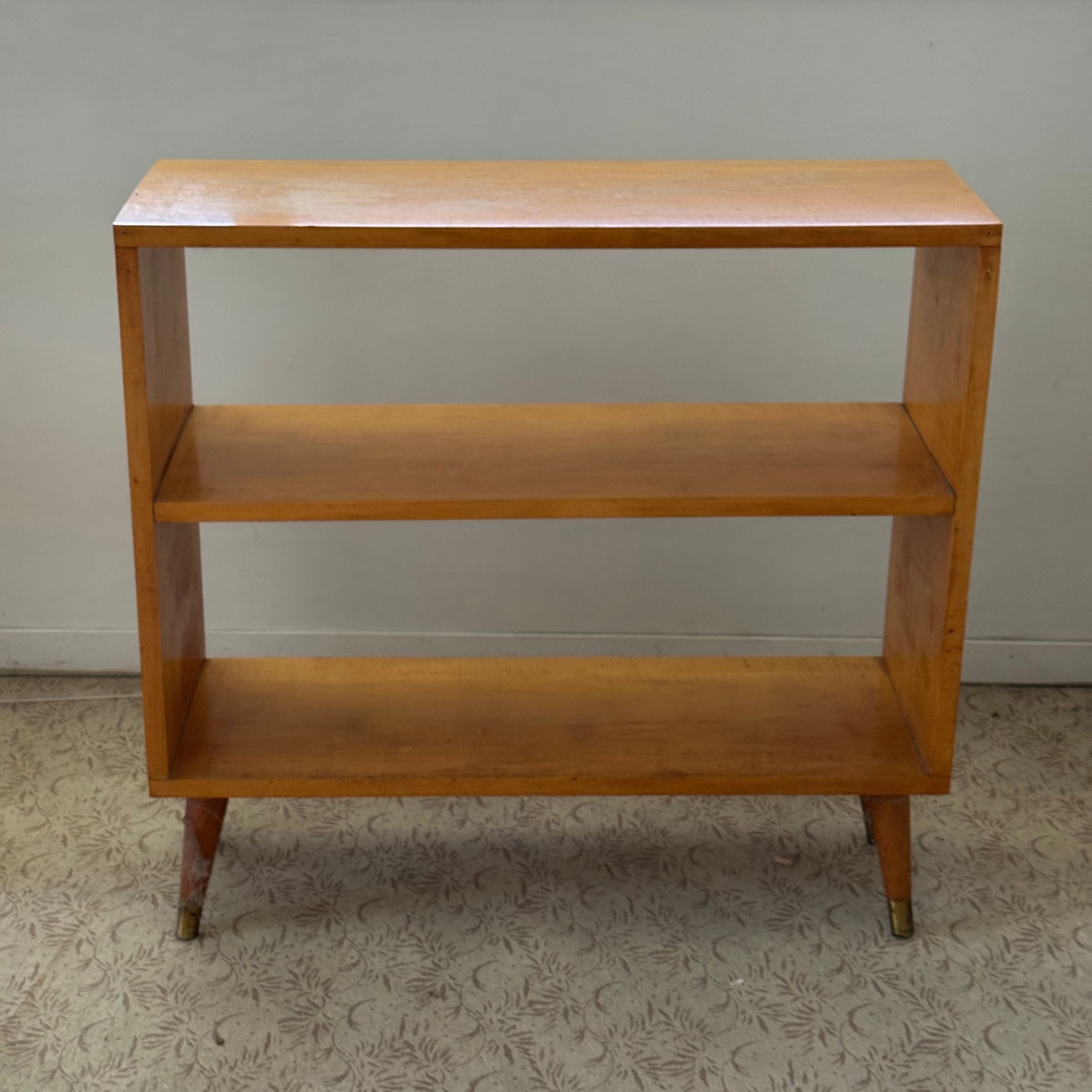 Mid Century Modern Wooden bookshelf with three shelves against a plain wall.